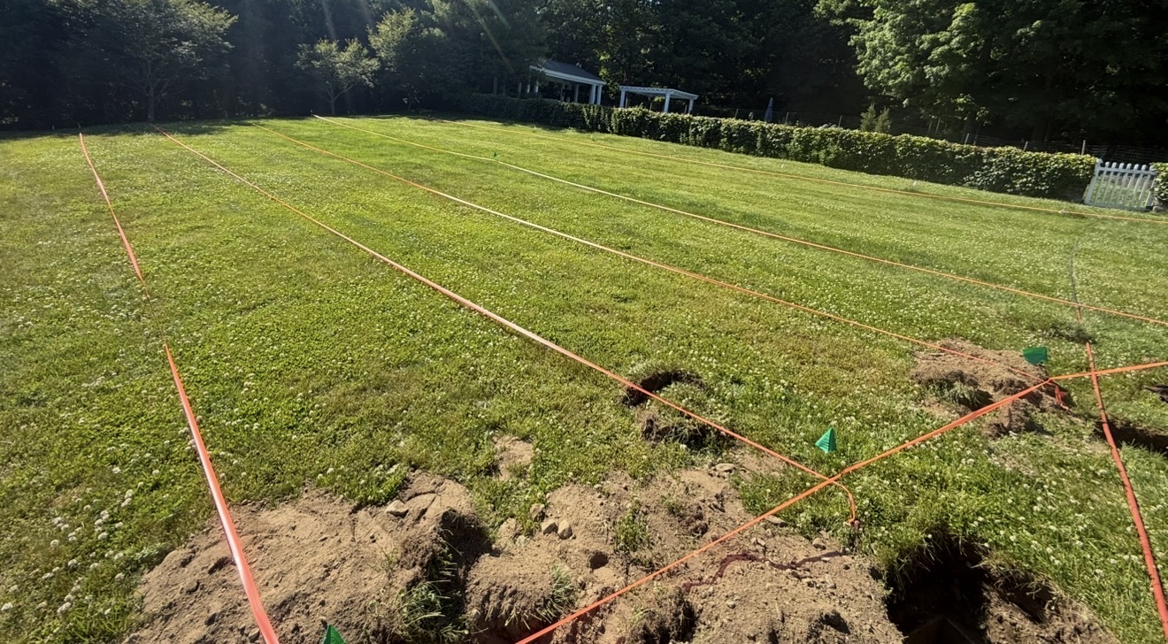 Septic drain field layout measured and marked with string lines and flags across a property