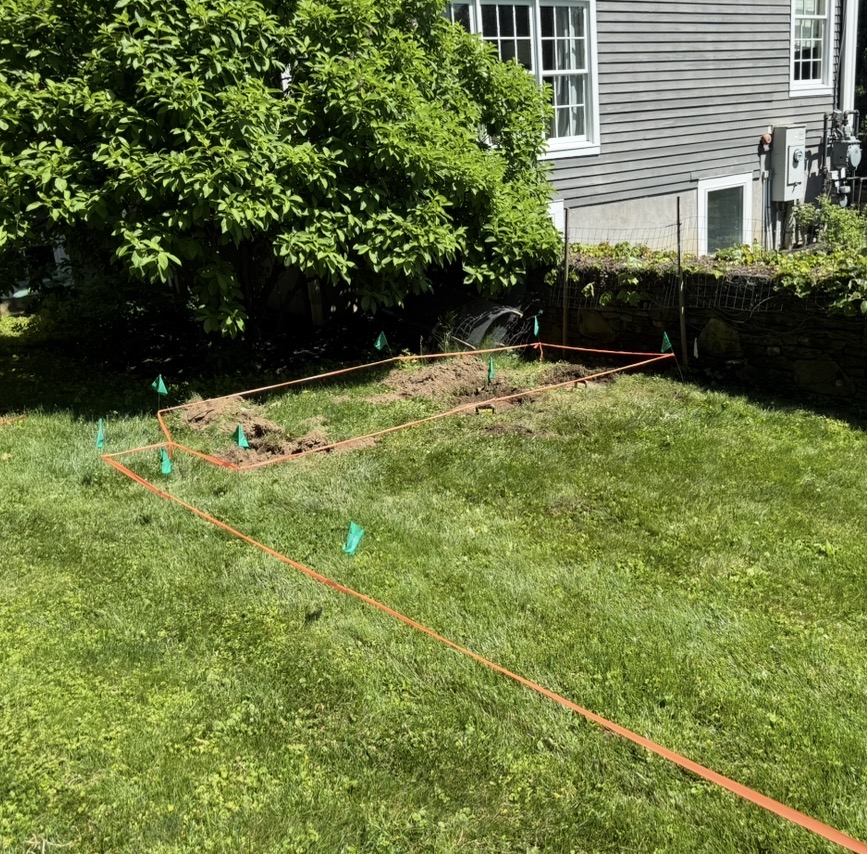 Septic system area staked and flagged for precise measurement in a Hudson Valley backyard